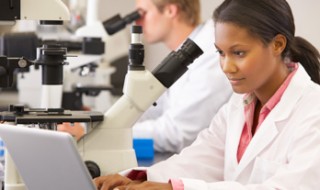 Male and female scientists using microscopes in a laboratory.