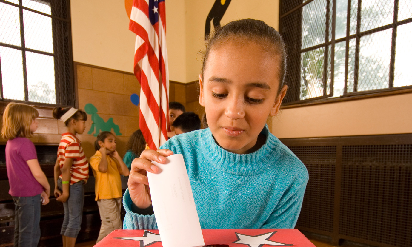 A girl placing a ballot into a ballot box during a school election.