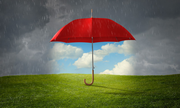 A red umbrella standing up by itself, keeping rain off the grass on a stormy day.