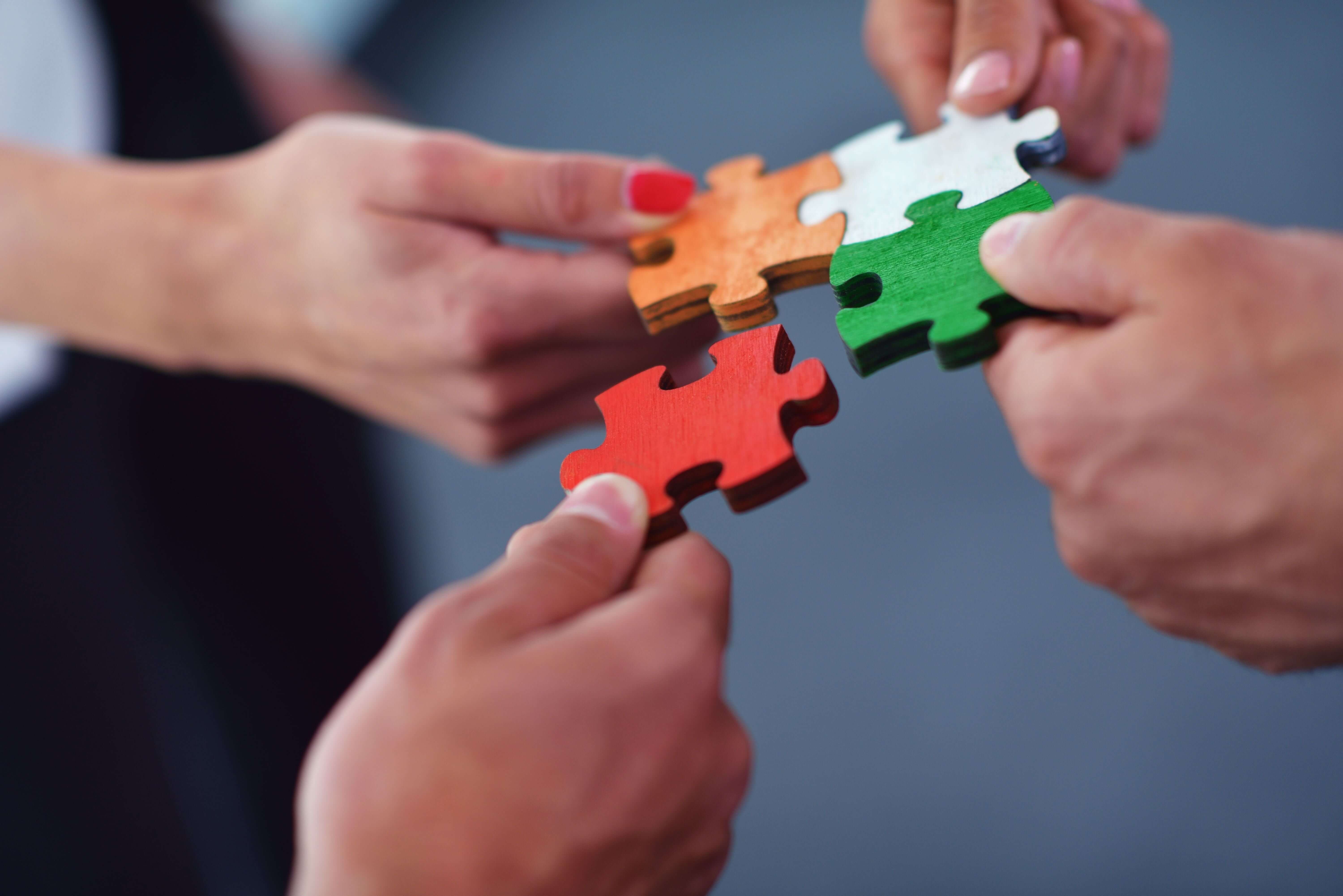 A group of people collaborate to fit together the pieces of a puzzle.