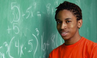 Portrait of a teenage boy smiling at the blackboard in a classroom