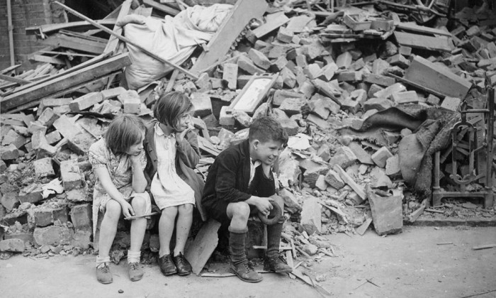 Children of an eastern suburb of London, who have been made homeless by the random bombs of the Nazi night raiders, waiting outside the wreckage of what was their home, World War II, 1940