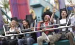 Blurred motion of three young women and young man on fairground ride, screaming