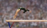 Female gymnast performing back flip on balance beam