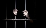 Hands of a prisoner on cell bars