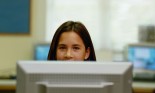 girl peering over computer screen