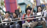 Blurred motion of three young women and young man on fairground ride, screaming