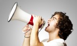 Young man shouting with megaphone against a grey background