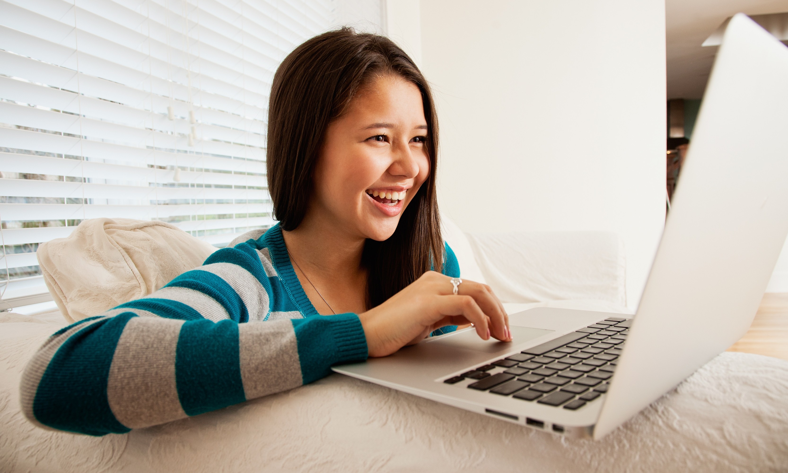 Teen girl (16-17 years old) in her living room, chatting online with friend...