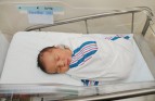 Healthy newborn infant baby boy sleeping in hospital bassinet wrapped in striped blanket just after birth