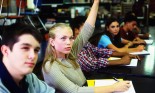 Teenage girl raises her hand in class.