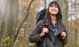 Smiling young woman with a backpack in the woods