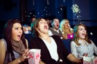 Group of young adult people sitting in the cinema and watching scary movie