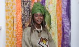 An African woman standing in front of colorful fabric