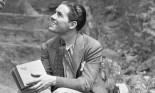 A man sitting outdoors holding a book