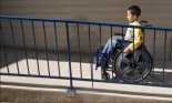 Boy in a wheelchair pushing himself up a wheelchair ramp