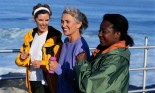 Three women exercising together by a bay