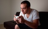 Young man playing a video game in a room lit by the television monitor