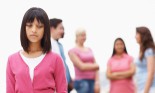 Girl looking forlorn standing apart from a group