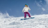 Young girl snowboarder in motion on snowboard in mountains