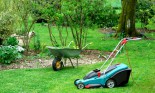 Electric lawnmower and a wheelbarrow in a beautiful garden