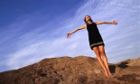 Woman Standing on Rock Face with Outstretched Arms