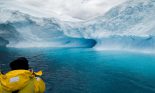 Rear view of a passenger taking a photo of an iceberg, Antarctica