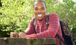 African American college student wearing backpack sitting at outdoor table