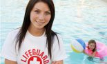 Female lifeguard next to swimming pool with girl in pool with a float