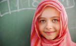Middle Eastern schoolgirl standing in front of blackboard