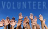 Volunteer group raising hands against blue sky background