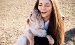 Girl holding dog while dog licks her face