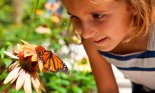 Girl (6-7 years old) looking at butterfly in garden, Hilton Head, South Carolina, USA