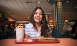 Teenage girl (14-15 years old) eating pizza in mall food court