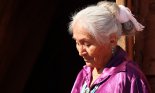 Elderly Navajo woman looking down outdoors in bright sun