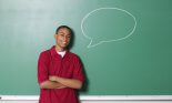 Portrait of teenage boy against chalkboard with speech balloon