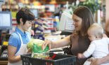 Mother and baby girl at checkout counter in supermarket