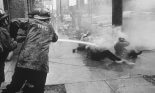 Firemen hose demonstrators with high pressure jets of water as they lie on the sidewalk, Birmingham, 1963