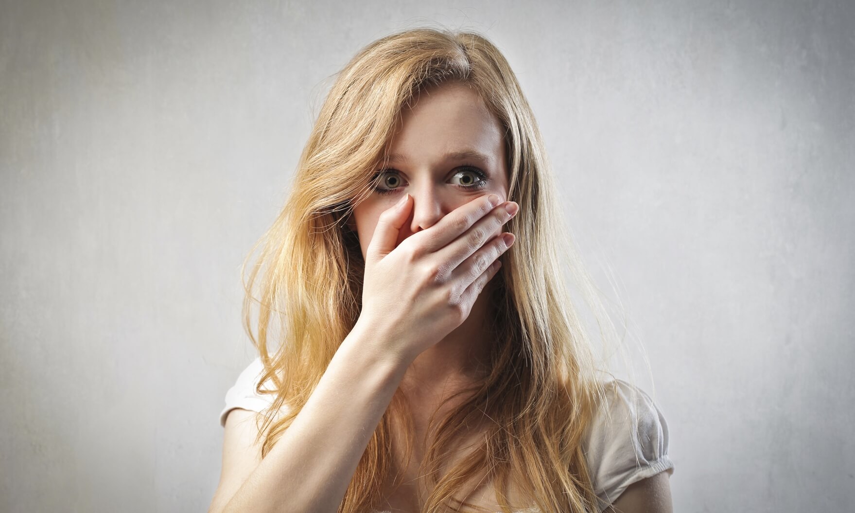 Scared young woman with her hand on her mouth