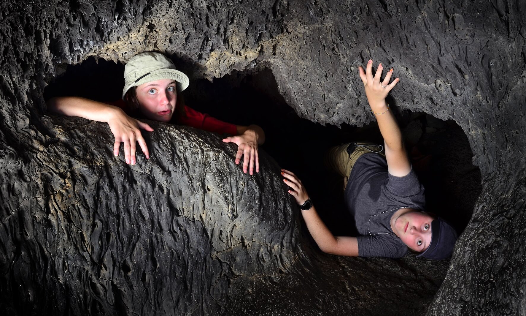 View of two kids exploring inside cave rocks