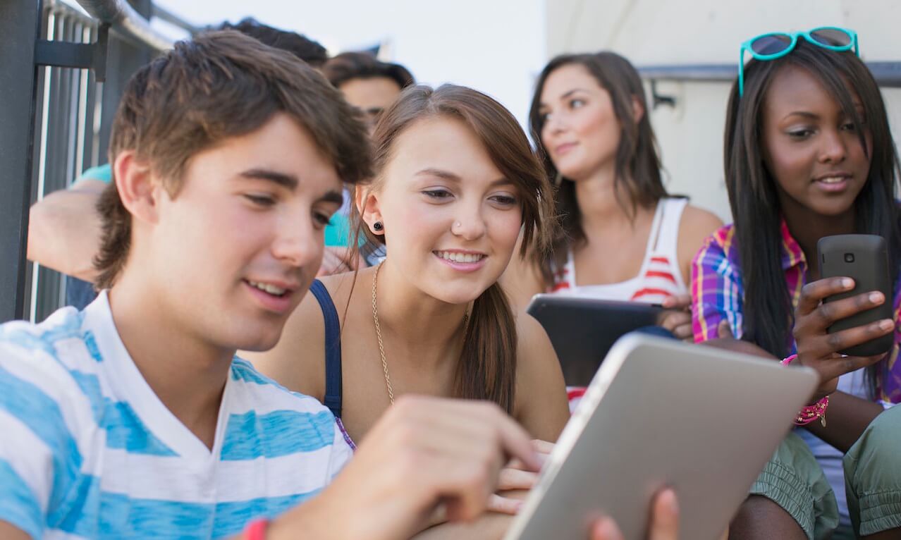 Teenagers sharing wireless technology outdoors