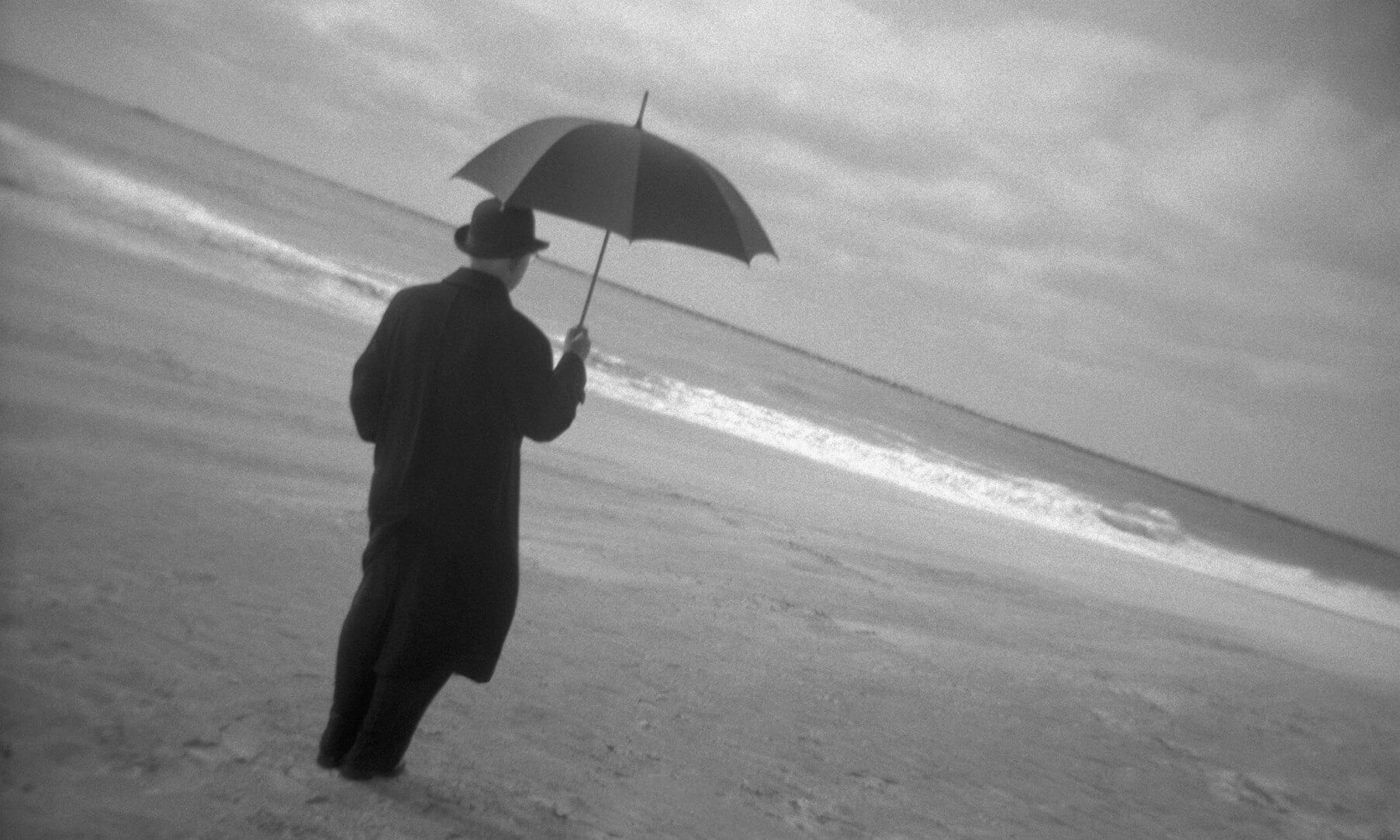 Man on Beach Holding Umbrella