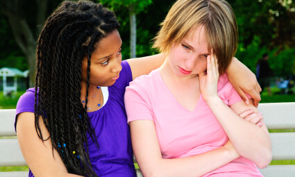 Teenage girl consoling her sad upset friend