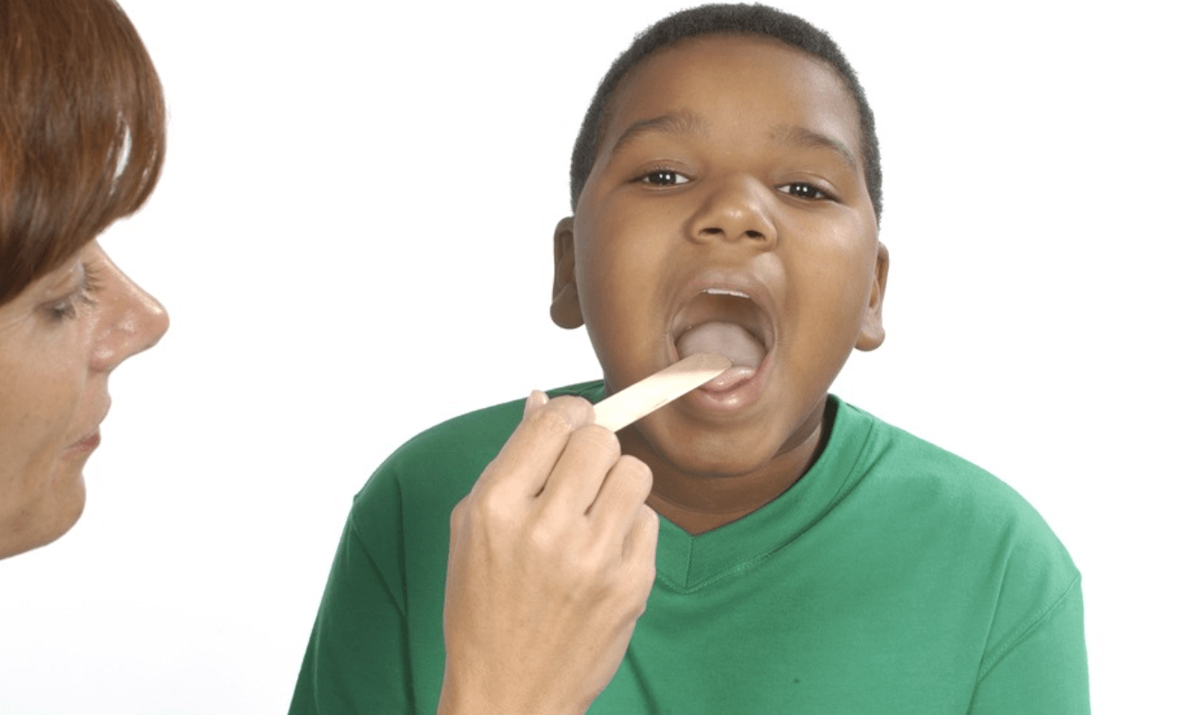 A doctor uses a tongue depressor to examine boy's throat