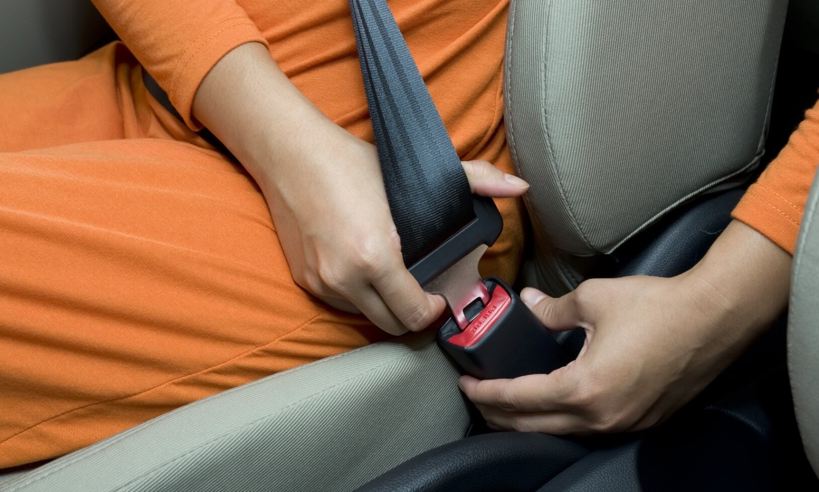 Woman sits on car seat fastening safety belt