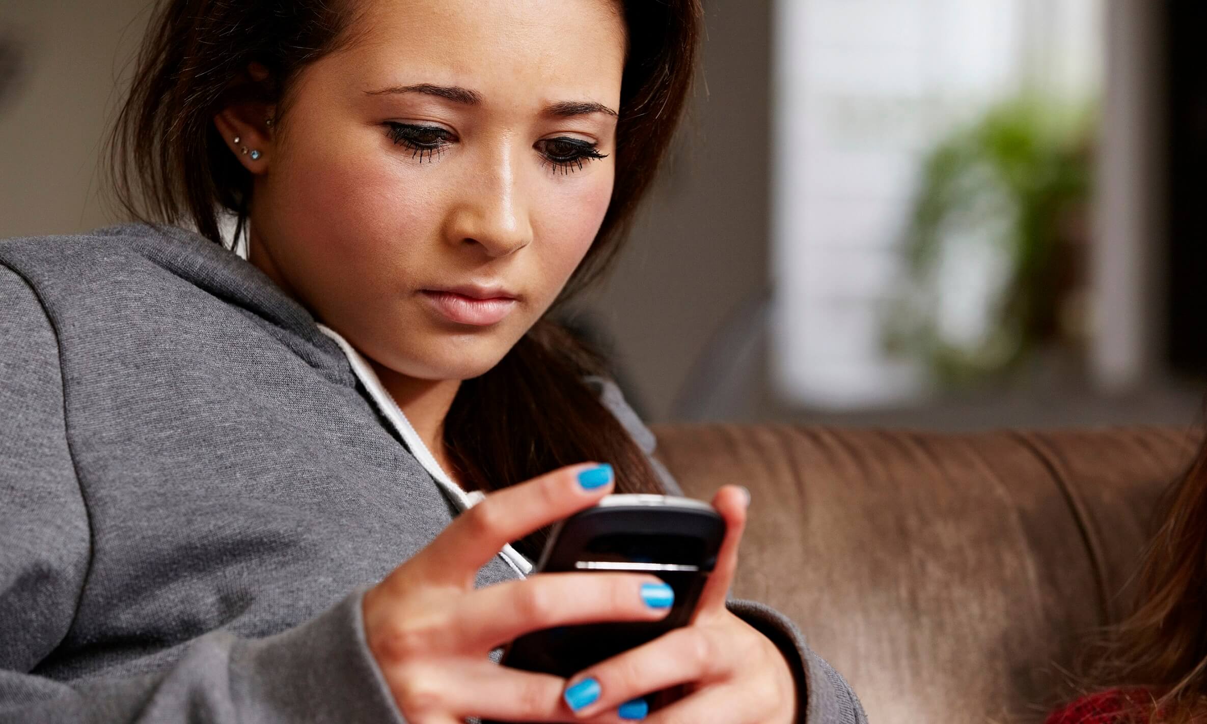 Teenage girl (16-17 years old) looking at cellphone, worried