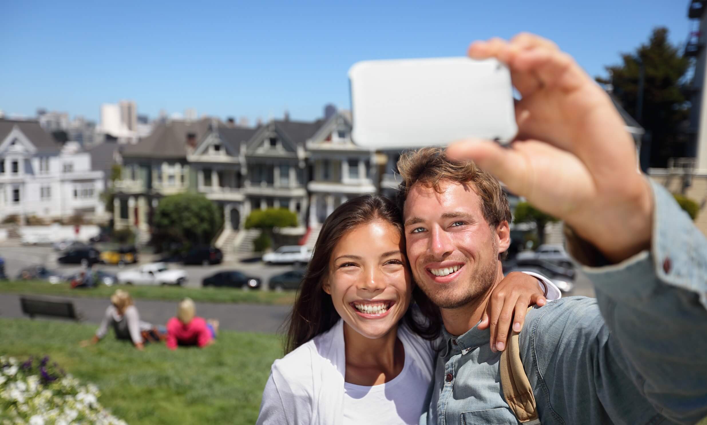 Happy young couple in San Francisco Alamo Square taking self-portrait with smart phone
