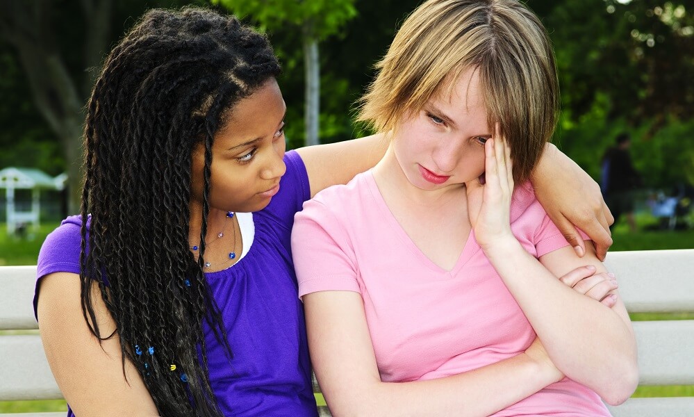 Teenage girl consoling her sad, upset friend