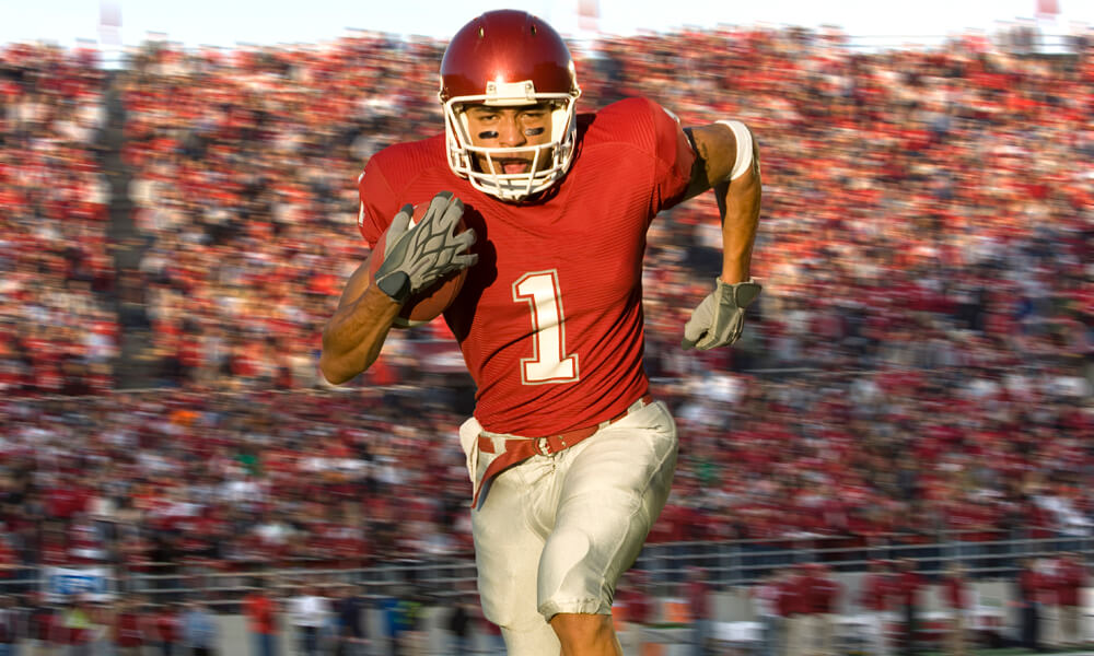 Football player running with football in a stadium