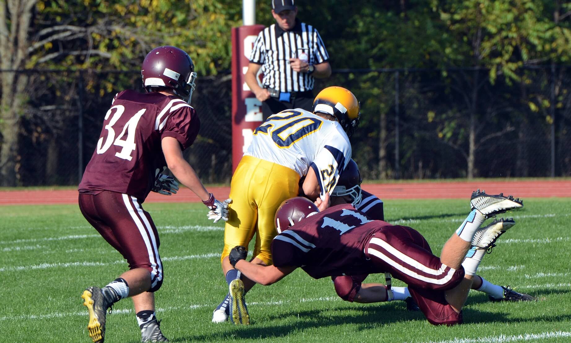 Football players making a tackle while referee watches